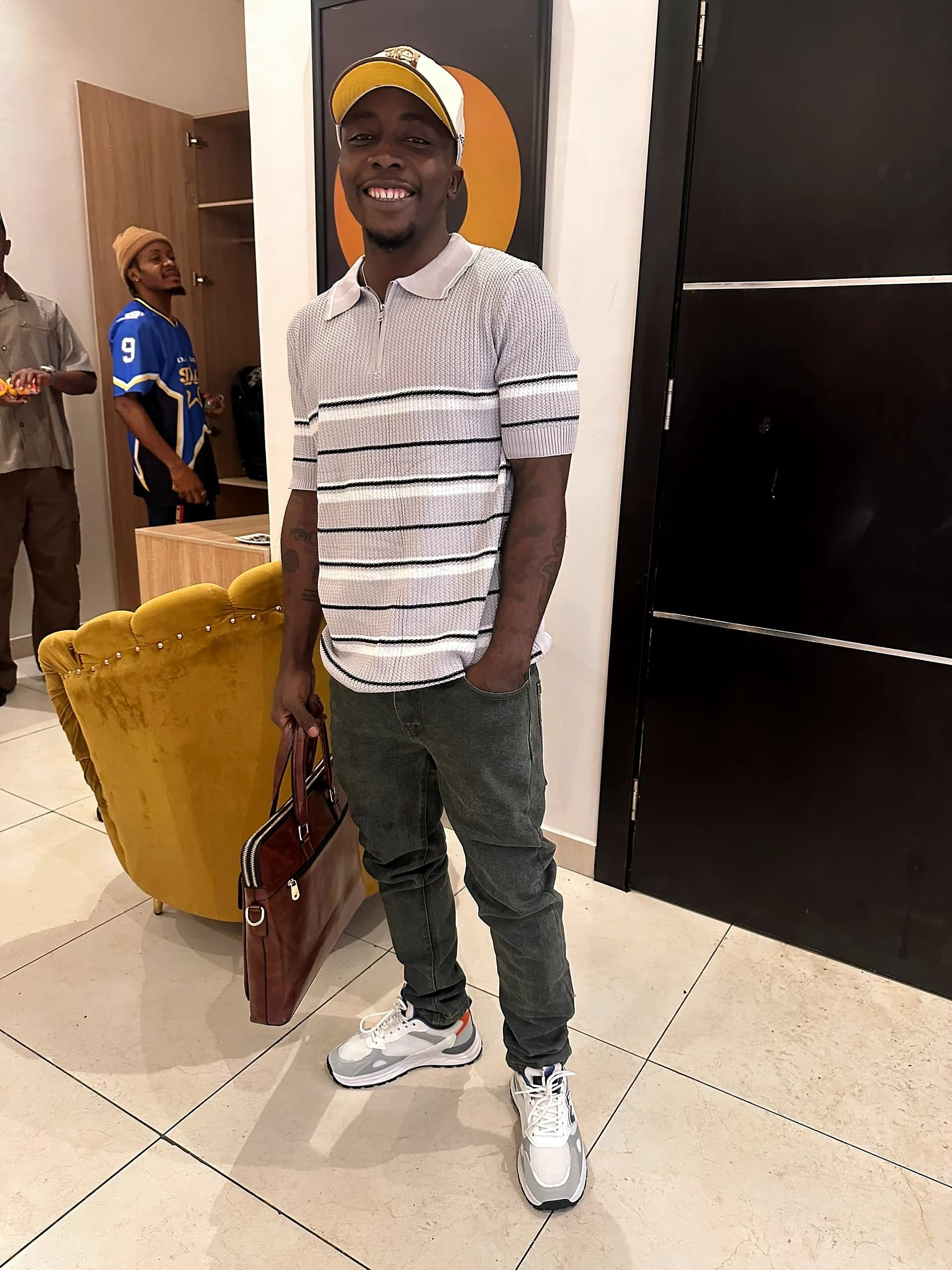 Tahnwi Lesley smiling while holding a briefcase